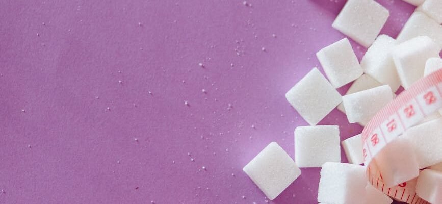 sugar cubes beside tape measure near dices with letter on a pink surface