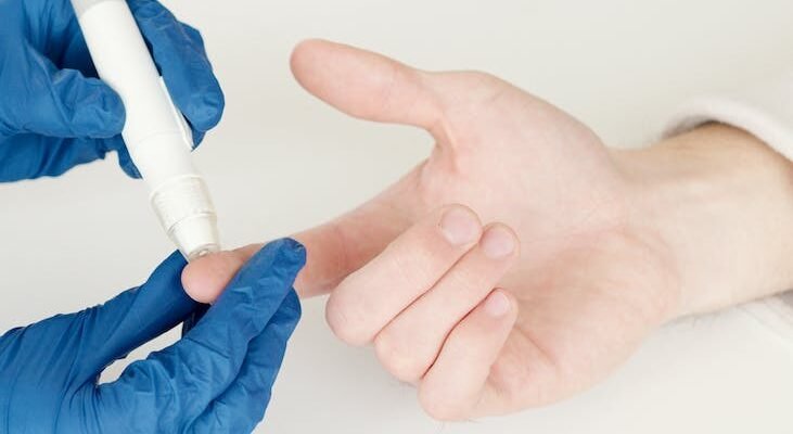 person in blue gloves using a lancet pen on a diabetic person